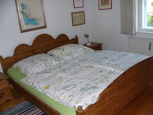 Helles Schlafzimmer mit einem großen Holzbett und bunten Bettwäsche.