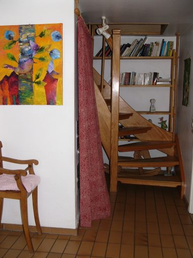 Holztreppe in einem Raum mit Bücherregal und einer gemusterten Wand.