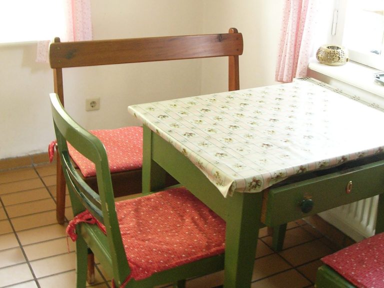 Ein kleiner Essbereich mit einem grünen Tisch und bunten Stühlen.