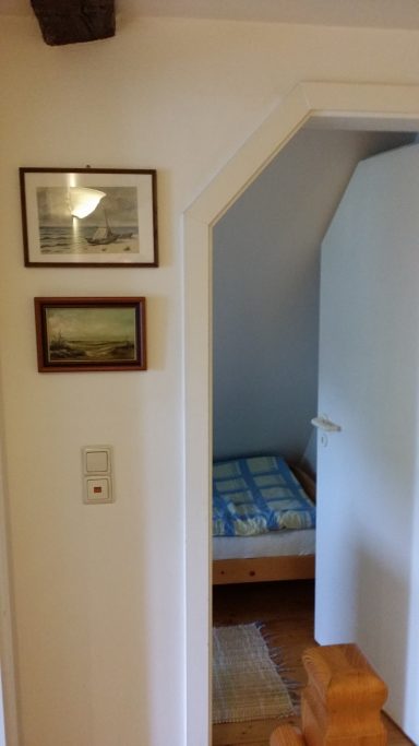 Blick durch einen Türbogen auf ein Schlafzimmer mit Bett und Wandbildern.