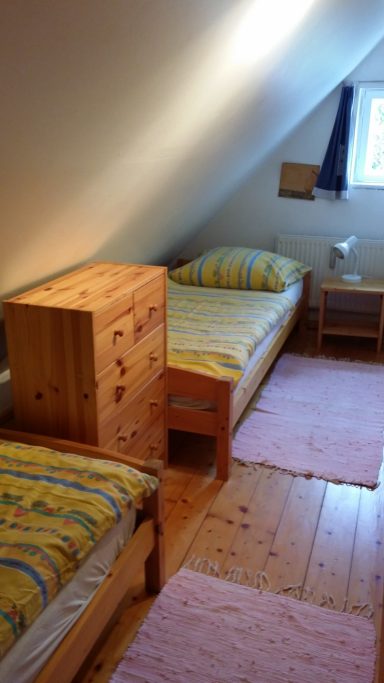 Gemütliches Schlafzimmer im Dachgeschoss mit zwei Betten und Holzmöbeln.