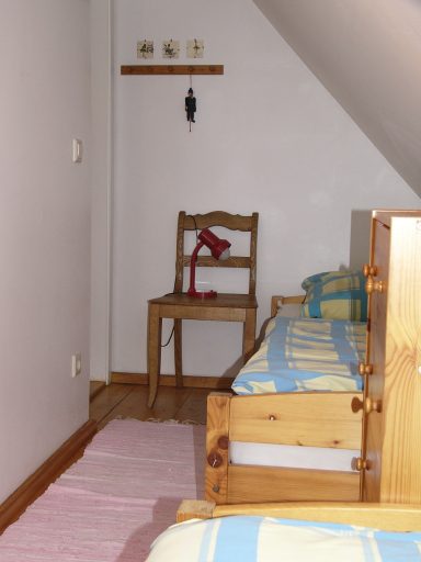 Kleines Zimmer mit zwei Betten, einem Stuhl und einer roten Lampe an der Wand.