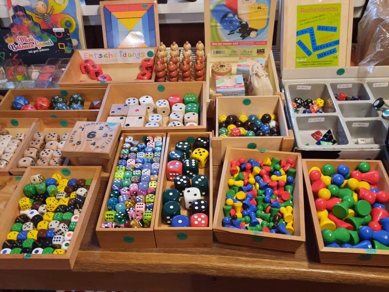 Bunte Spielzeugfiguren und -würfel in Holzkisten, farbenfrohe Auswahl.