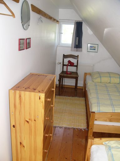 Kleines Schlafzimmer mit zwei Betten, Kommode, Stuhl und Fenstern.