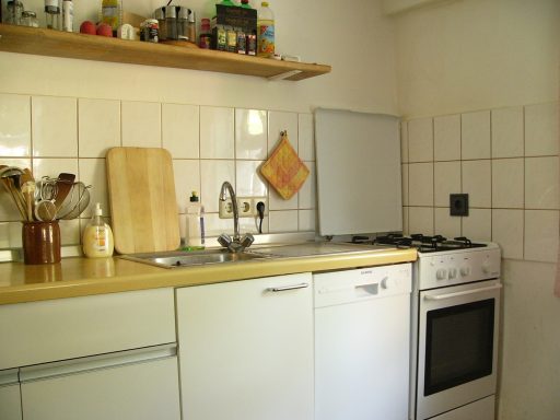 Küche mit Spüle, Herd, Holzbrett und Regal voller Gewürze.