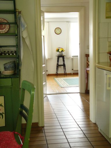 Heller Flur mit Zugang zu einem Raum, einem Hocker und einem Teppich im Hintergrund.