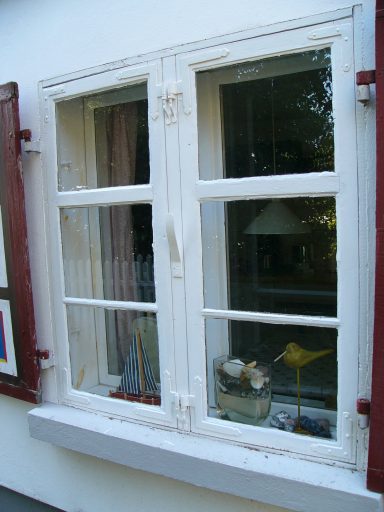 Weißes Fenster mit Holzrahmen und Blumentopf auf der Fensterbank.